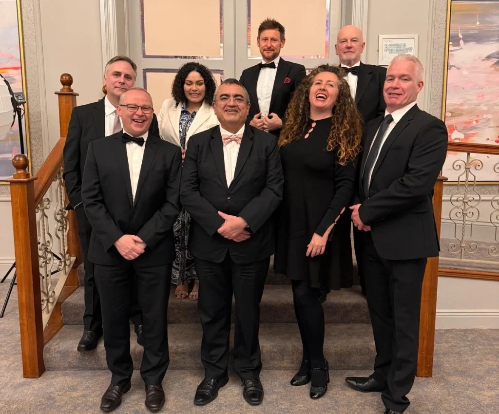Group of eight people in formal attire, smiling and posing for a photo at the Education Awards 2024 at the Education Awards 2024
